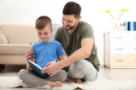 Father and son reading book at homeの写真素材