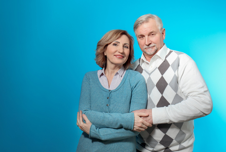 Happy senior couple holding hands on color backgroundの写真素材