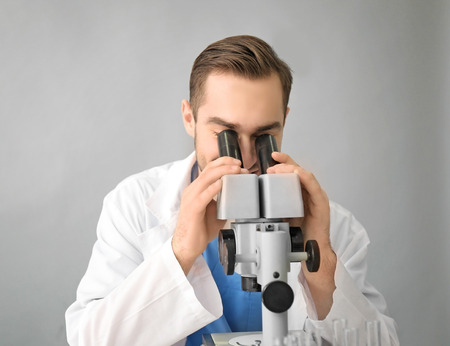 Handsome young scientist testing samples, on light background