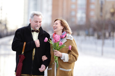 Happy senior couple with bouquet of flowers  on a walkの写真素材