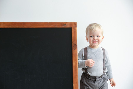 Cute little boy and blackboard on light backgroundの写真素材