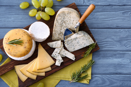 Cutting board with sliced assorted cheese on wooden backgroundの写真素材
