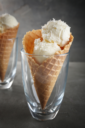 Glass with waffle cone and balls of coconut ice cream on grunge backgroundの写真素材