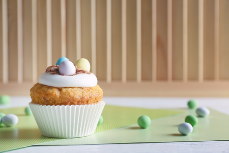 Decorated Easter cupcake on white table with green table-napkin