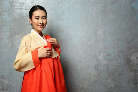 Beautiful young woman dressed in traditional clothing on grey backgroundの写真素材