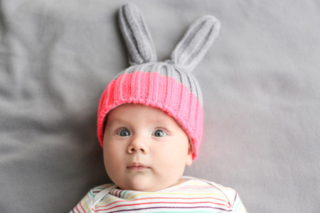 Cute little baby in bunny hat lying on soft blanketの写真素材