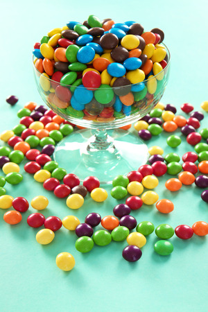 Delicious colorful candies in bowl on color backgroundの写真素材