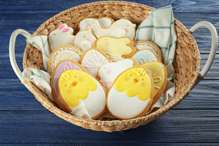 Basket with glazed Easter cookies on wooden table