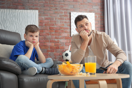 Father and son watching football on TV at homeの写真素材