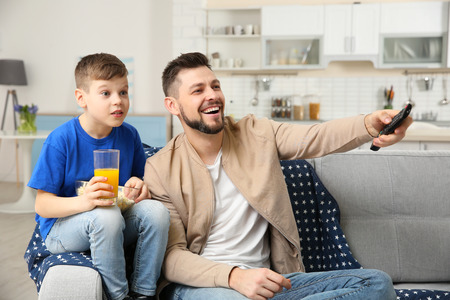 Father and son watching sports on TV at homeの写真素材