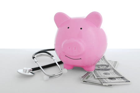 Ceramic piggy bank with stethoscope and dollar banknotes on white backgroundの写真素材