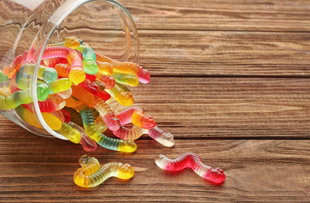 Glass jar with tasty jelly worms on wooden backgroundの写真素材
