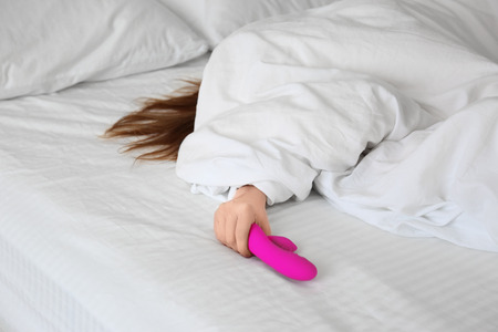 Woman holding dildo in bedの写真素材