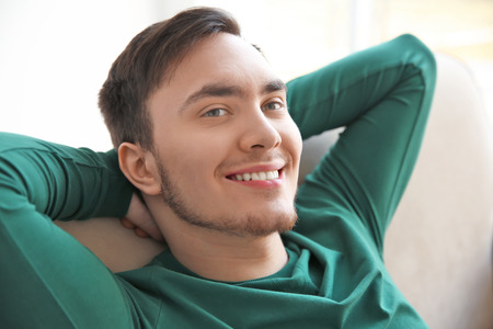 Happy young man resting on sofaの写真素材