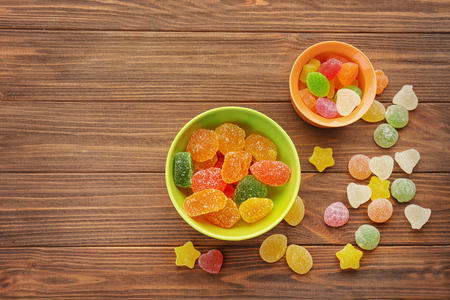 Bowls with tasty jelly candies on wooden backgroundの写真素材