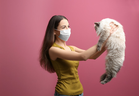 Animal allergy concept. Beautiful woman with cat on color backgroundの写真素材