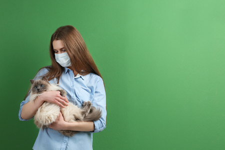 Animal allergy concept. Beautiful woman with cat on color backgroundの写真素材