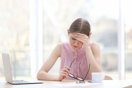 Beautiful young woman suffering from headache in officeの写真素材