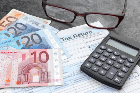 Tax return form, glasses, calculator and euro on tableの写真素材