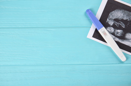 Ultrasound photo and pregnancy test on blue wooden backgroundの写真素材