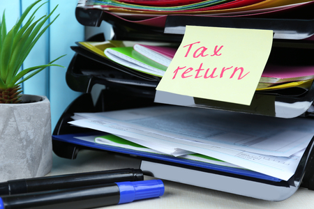 Note with TAX RETURN text, forms and stationery on tableの写真素材