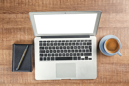 Laptop, notebook, pen and cup of coffee on wooden tableの写真素材
