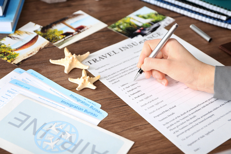 Woman filling in blank travel insurance form on tableの写真素材