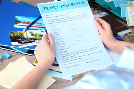 Woman sitting at workplace and holding blank travel insurance form, closeupの写真素材