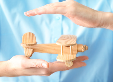 Female hands and wooden toy airplane. Travel insurance conceptの写真素材