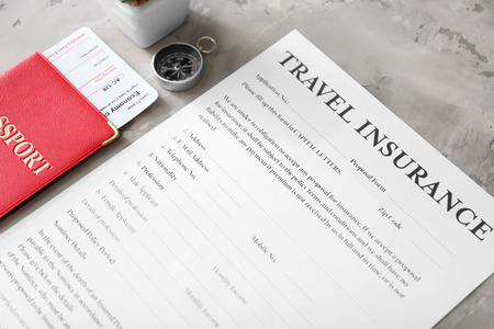 Passport with ticket and blank travel insurance form on grey background