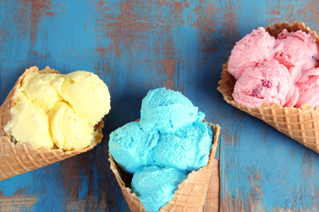 Different ice cream in waffle cones on wooden background