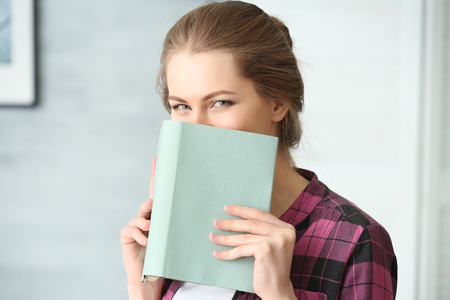 Beautiful young woman with book at homeの写真素材