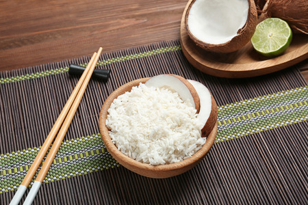 Wooden bowl with coconut rice on bamboo mat