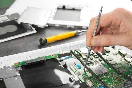 Man fixing dismantled laptop on table. Concept of computer repair