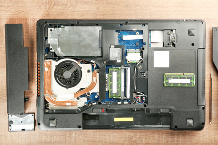 Dismantled laptop on wooden table. Concept of computer repair