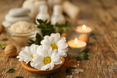 Beautiful spa composition with flowers and candles on wooden tableの写真素材