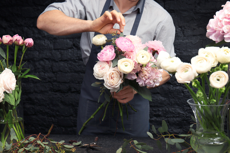 Male florist creating beautiful bouquet in flower shop, close upの写真素材