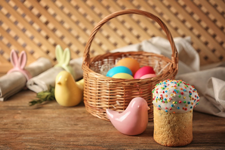 Easter cake with decorative bird and basket on wooden table