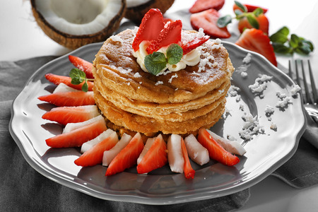 Stack of delicious coconut pancakes with strawberry and butter cream on napkinの写真素材