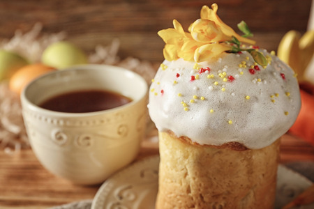 Plate with Easter cake and cup on wooden background