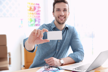 Handsome young designer with business card in officeの写真素材