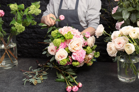 Male florist creating beautiful bouquet in flower shop, close upの写真素材