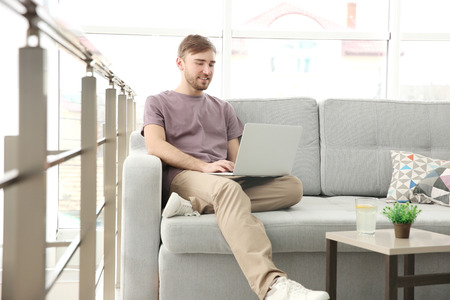 Handsome young man with laptop at homeの写真素材