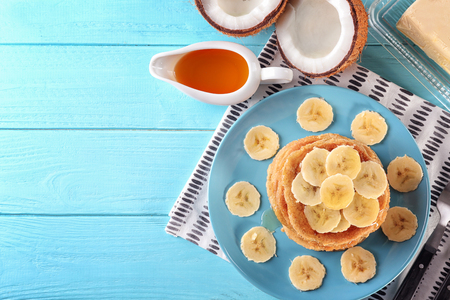 Stack of delicious coconut pancakes with sweet sauce and sliced banana on tableの写真素材