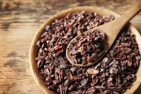 Wooden bowl and spoon with cocoa nibs on tableの写真素材