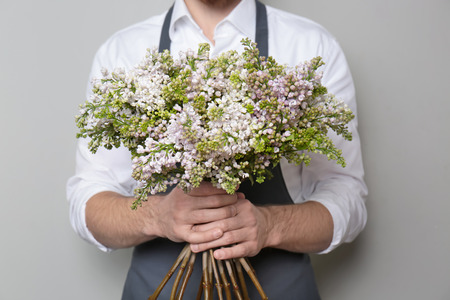 Young florist with beautiful bouquet on grey backgroundの写真素材