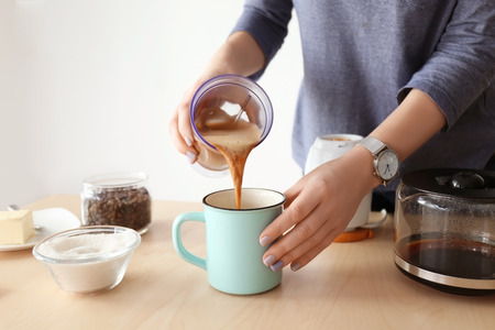 Woman pouring coffee with butter into mug, closeupの写真素材