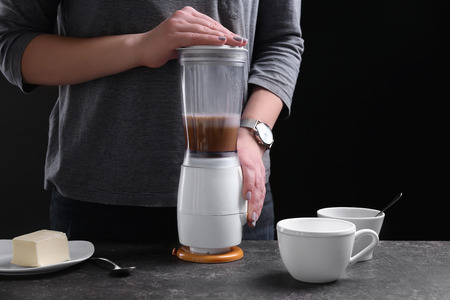 Woman using blender to make coffee with butter, closeup
