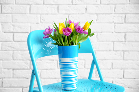 Vase with bouquet of beautiful tulips on chairの写真素材