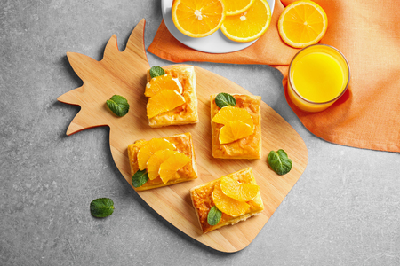 Cutting board with delicious pastries and slices of orange on grey tableの写真素材